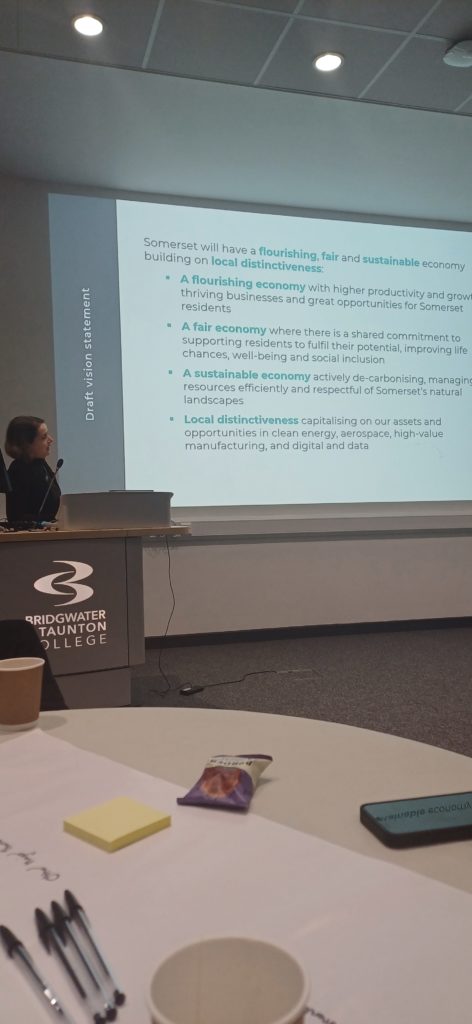 A photo of a woman at Bridgwater & Taunton College speaking next to a projected presentation