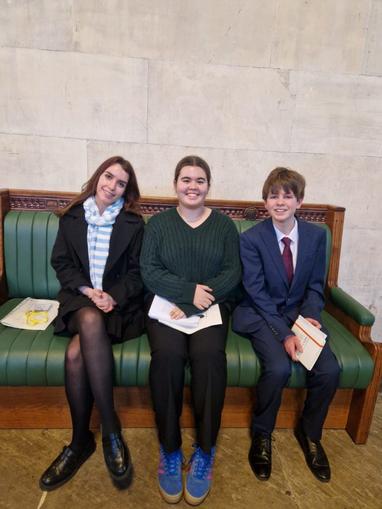 The three Somerset Members of Youth Parliament sit on one of the green benches in the House of Commons