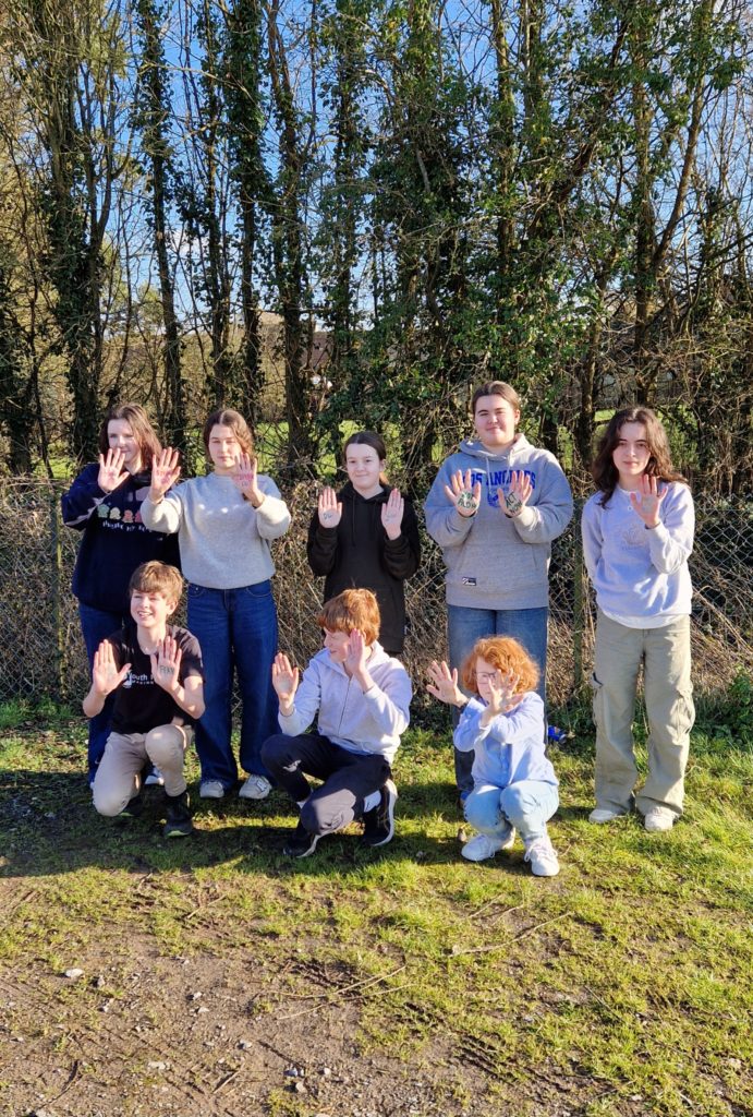 Eight members of the Youth Parliament Advisory Group stand in two rows with their hands out and their Child Exploitation Awareness Day pledges written on their palms